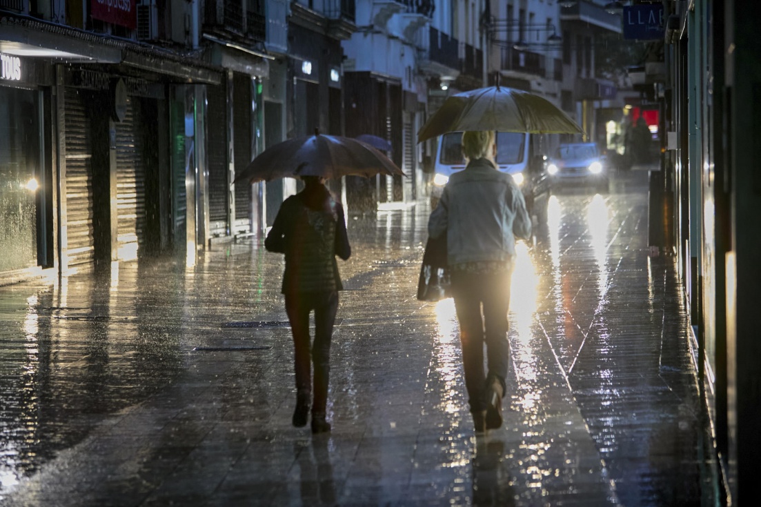 Imagen de archivo de dos personas se protegi&eacute;ndose de la lluvia con un paraguas . EFE/Natxo Franc&eacute;s/Archivo