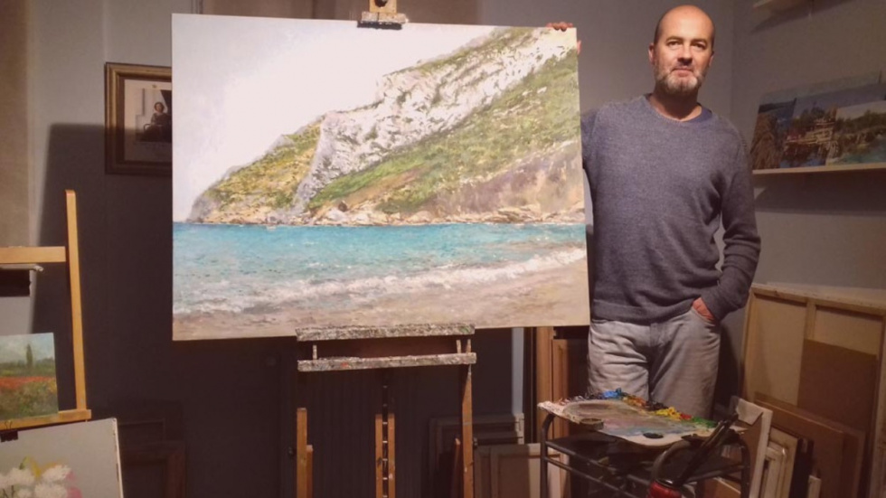 Fig. 1. Rub&eacute;n de Luis en su estudio con la obra La Cala Granadella (2019. O/l, 86 x 116 cm)