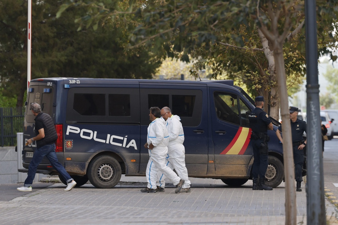 Efectivos de los servicios funerarios junto a un furg&oacute;n policial. EFE/ Ana Escobar